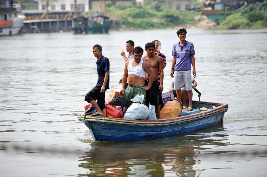 2013年10月4日，海南琼海，几位渔民正乘接驳的小船返回潭门港码头。当天上午，受台风“蝴蝶”袭击的海南琼海市渔船已陆续安全返回潭门港。