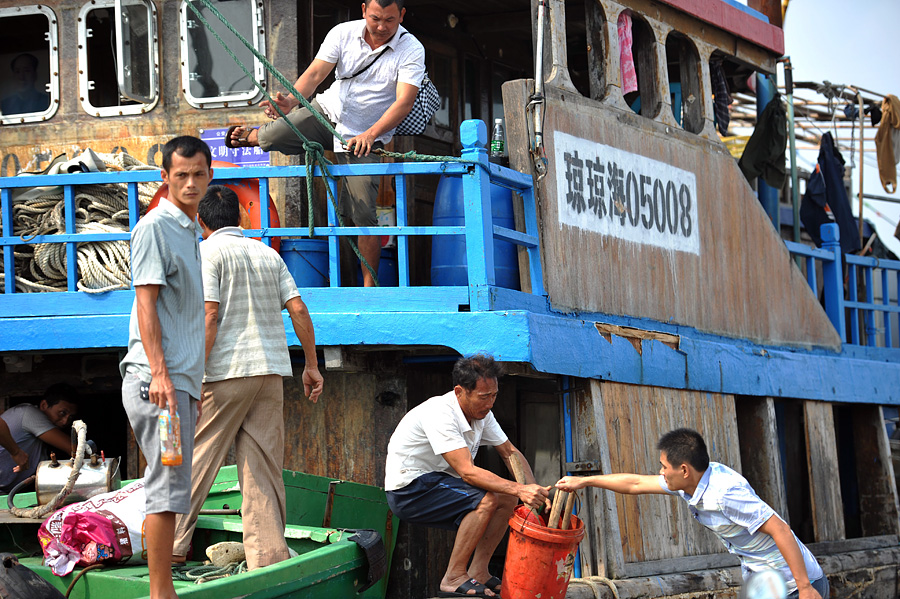 2013年10月4日，海南琼海，渔民正在潭门港码头卸行李。当天上午，受台风“蝴蝶”袭击的海南琼海市渔船已陆续安全返回潭门港。