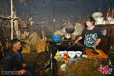 高发常和儿媳在茅草屋内煮饭。 中国网图片库 周会/摄