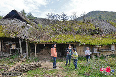 几位孩子和大人在三峡库区奉节县长安土家族乡五坝村保存较为完整的草屋前玩耍（10月7日摄）。 中国网图片库 周会/摄