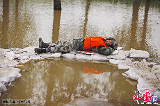 抗洪期間，一名疲憊的戰士躺在洪水之間的沙袋上和衣而睡。  中國網圖片庫  魏建順/攝　