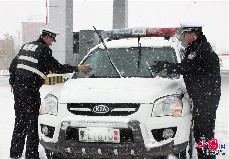 10月13日，在301国道内蒙古牙克石市境内，交警在雪中疏导交通。 中国网图片库 王伟/摄