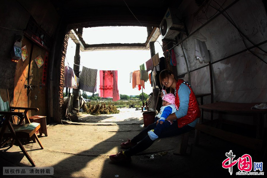 年轻的母亲一边哄孩子一边还在打电话聊天。中国网图片库 李瑞昌/摄