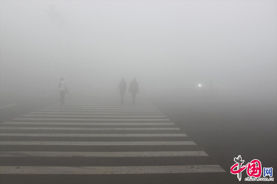 2013年10月21日，大霧能見度不足十米，行人過馬路小心翼翼，汽車行駛至路口彼此鳴笛判斷對方位置。中國網圖片庫 知言攝影