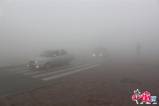 2013年10月21日，大雾能见度不足十米，行人过马路小心翼翼，汽车行驶至路口彼此鸣笛判断对方位置。中国网图片库 知言/摄