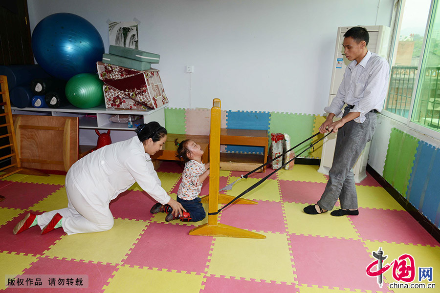 李艷向家長們傳授康復訓練技術動作。在這些患兒家長眼裏，李艷總是帶著和藹的笑容跪著為孩子做訓練。 中國網圖片庫 周會/攝