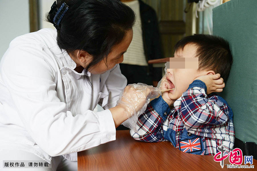  李艳在为脑瘫儿童做口语康复训练。2000年到2009年，她曾到中国康复研究中心进修，取得了结业证书，并被该中心聘为康复师。中国网图片库 周会/摄 