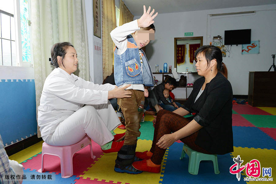 通过李艳（左）的康复训练，10岁的脑瘫儿童熊歇宇能站立起来了，母亲张茂群（右）激动不已。 中国网图片库 周会/摄 
