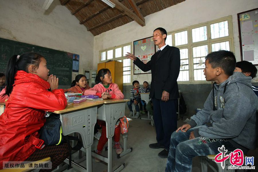 刘老师站着孩子们周围，孩子们那渴望和专注的神情是他一直坚持义务授课的动力。中国网图片库 胡卫国/摄