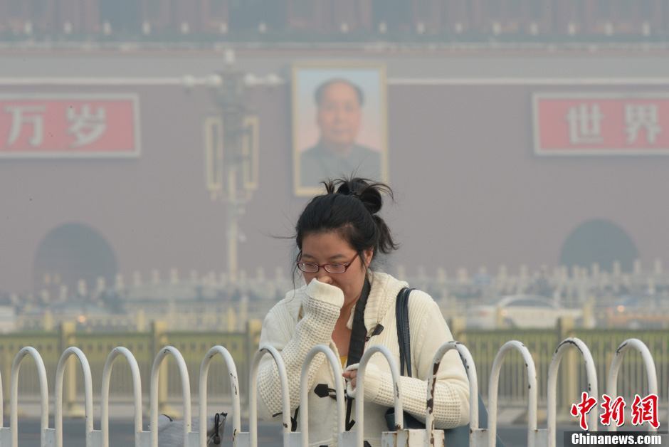 10月28日，北京天安门广场的一名路人掩面而行。当天，北京长安街被雾霾笼罩，能见度不高。今早的北京雾霾弥漫，许多出门的市民都感觉呼吸不舒服。