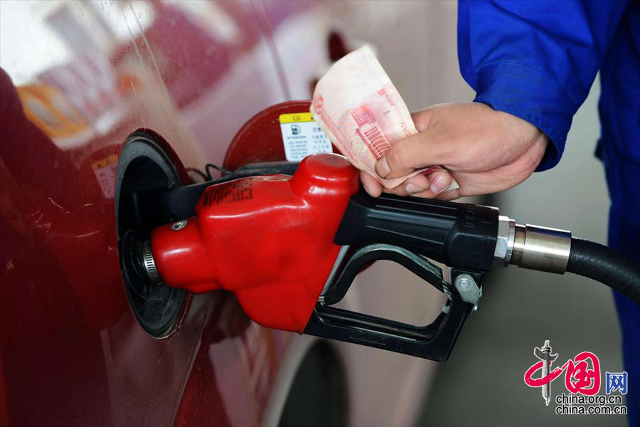 2013年10月31日，山东青岛一加油站工作人员在给车辆加油。