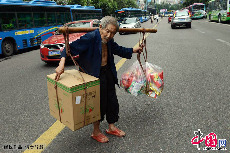 甘在思挑着货物步履蹒跚地穿梭于人群和车流中。中国网图片库 周会/摄