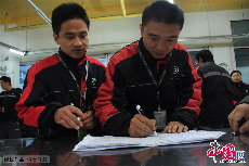 2013年11月11日清晨，位于山东济南历下区配送点，两名工作人员在签字记录考勤情况。中国网图片库 郭志华/摄