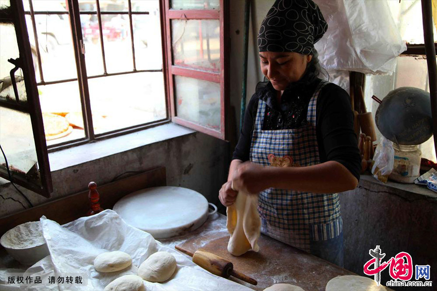 平時庫爾班的妻子負責做面餅，租住的地方不算寬敞但臉上的笑容充滿了希望。中國網圖片庫孫繼虎/攝