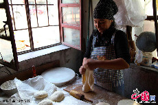 平時庫爾班的妻子負責做面餅，租住的地方不算寬敞但臉上的笑容充滿了希望。中國網圖片庫孫繼虎/攝