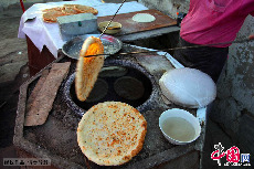 每天早晨，庫爾班先烤蔥花囊，因為哈密人早餐喜歡吃蔥花馕。庫爾班從囊坑中取出一個金黃色蔥花馕。中國網圖片庫 孫繼虎/攝
