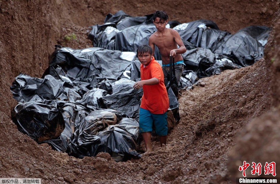 11月14日，菲律賓萊特省首府塔克洛班市，工人將颱風中的遇難者屍體集中挖坑埋葬。據菲律賓社會福利部提供的數據，強颱風“海燕”侵襲菲律賓造成的遇難人數是4460人，另有92萬人流離失所，災民人數總計達1180萬人。