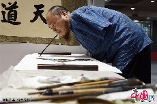 2013年11月7日，无臂残疾人黄国富用嘴执笔作画。中国网图片库 周会/摄