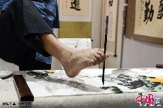 2013年11月7日，无臂残疾人黄国富用脚执笔作画。中国网图片库 周会/摄