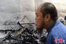 2013年11月7日，无臂残疾人黄国富用嘴执笔作画。中国网图片库 周会/摄