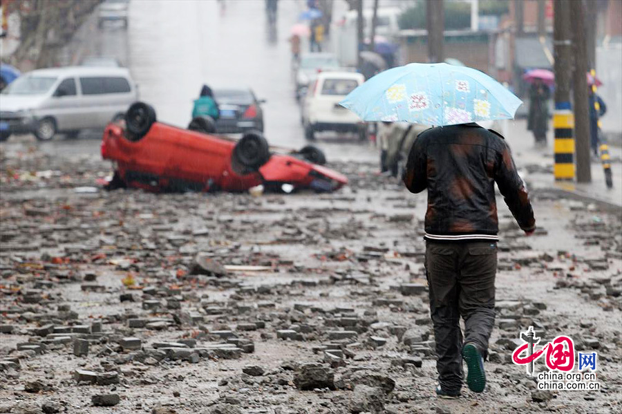 2013年11月24日，青岛漏油燃爆事故现场，一名在雨中回家的居民走在尚未清理干净的马路上。22日中石化黄潍输油管线一输油管道发生破裂并起火燃爆。