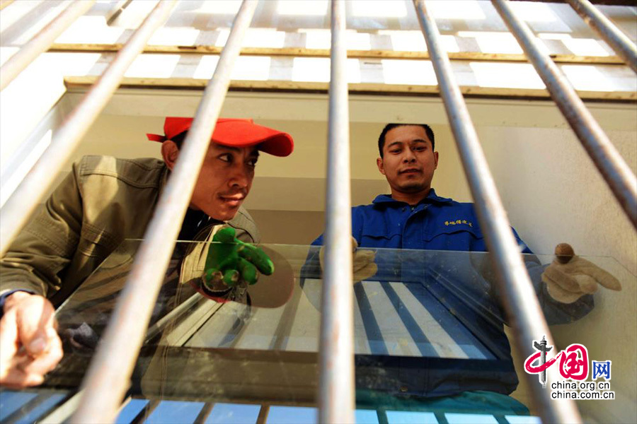 2013年11月25日，山东青岛开发区盈泰小区工作人员在帮助受损居民更换窗户玻璃。