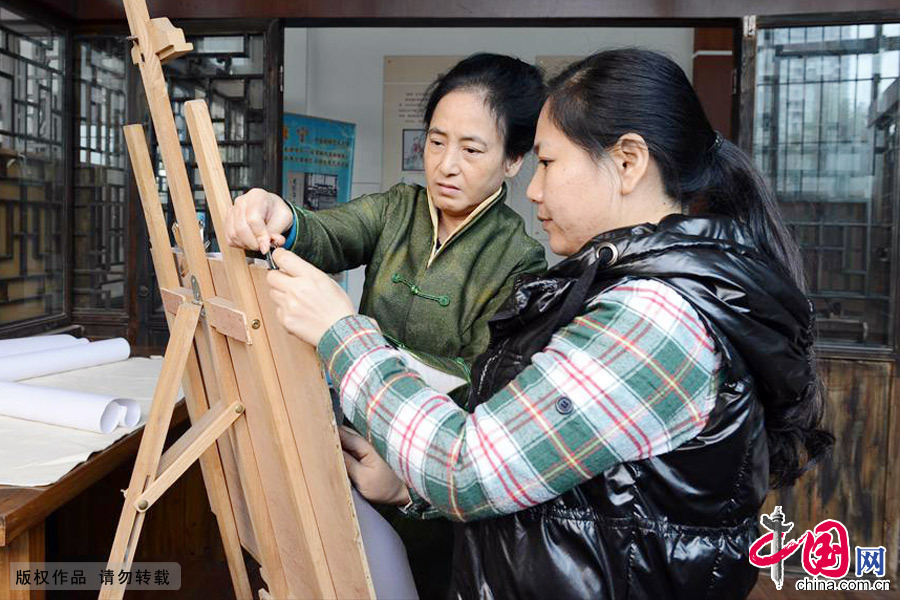 康宁（左）与徒弟在整理绣架。中国网图片库 周会/摄