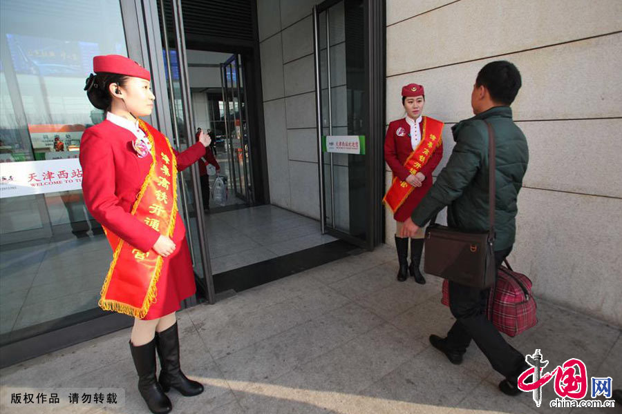 2013年12月1日，天津西站一樓門口工作人員佩帶綬帶迎接津秦高鐵首批乘客。