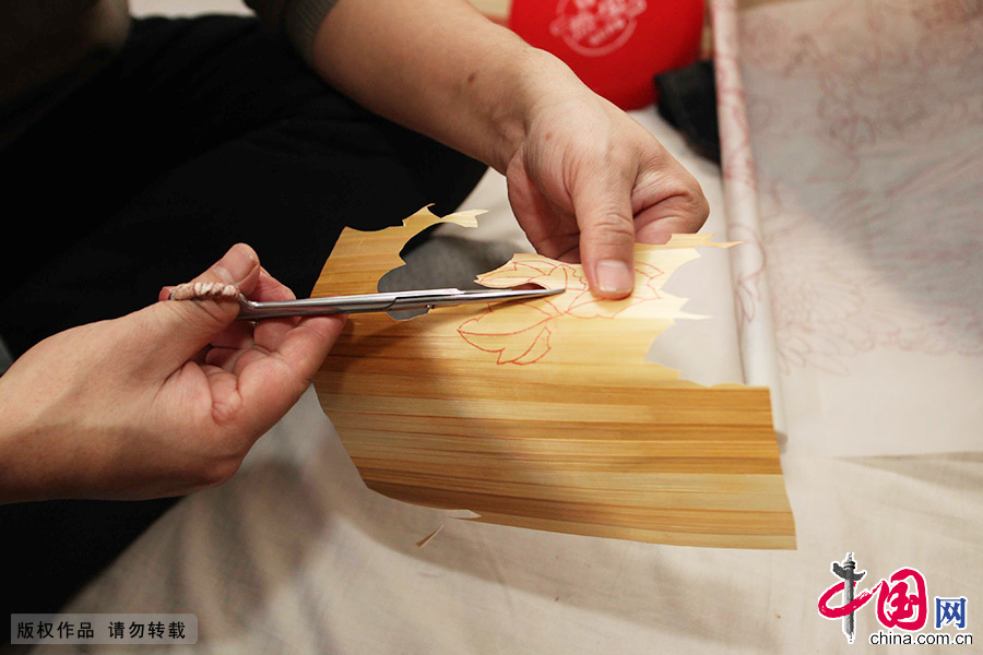 老王将处理过的麦秆皮剪成不到一厘米的小段，然后用剪刀快速剪成流苏状，一点一点拼接成所需要的形状。中国网图片库 澎湃/摄 