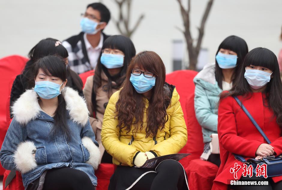 12月6日，戴著口罩的市民在南京街頭觀看表演。受持續霧霾“圍”城的影響，南京空氣重度污染，一些防護用具及凈化空氣工具的銷量大增，PM2.5口罩更是一度脫銷。
