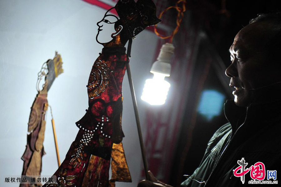 2013年12月11日，湖北民間藝人徐成樹在第二屆皮影戲後臺操作人物道具。中國網圖片庫 張國榮/攝