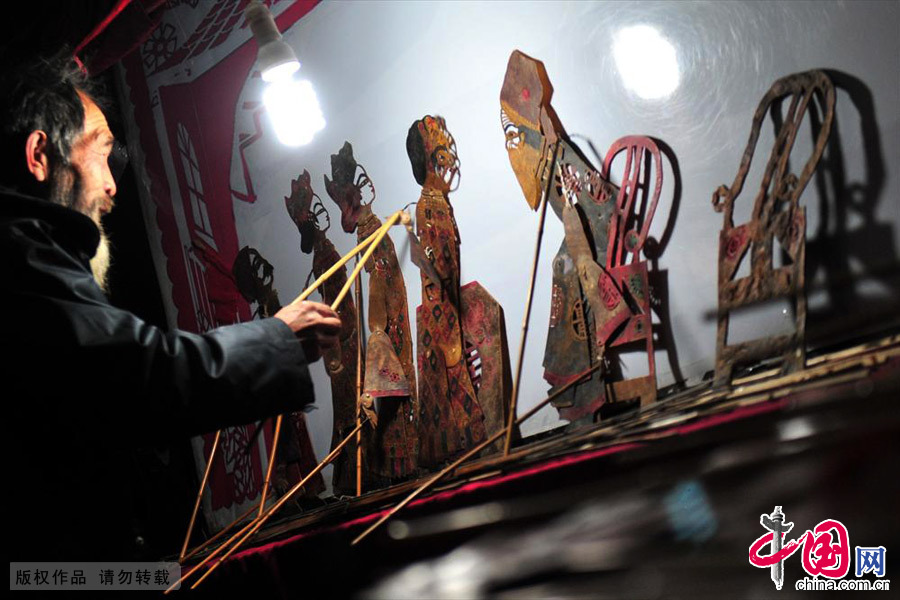 2013年12月11日，湖北省宜昌市夷陵区民间艺人在后台表演皮影戏。中国网图片库 张国荣/摄