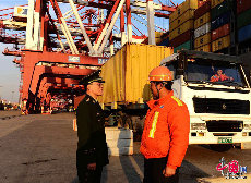 2013年12月10日，山东青岛前湾保税港区外贸集装箱码头一位边检站干警在与码头工人交流。（中国网图片库 俞方平摄影）