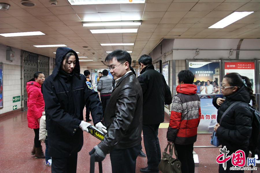 2013年12月16日，北京天安門東站地鐵站內(nèi)安檢員對(duì)乘客進(jìn)行安檢。中國網(wǎng) 李佳攝影