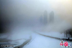 2013年12月17日，吉林省吉林市被大霧籠罩，城市建築時隱時現，市民和車輛在霧霾中前行。中國網圖片庫 老萬攝  