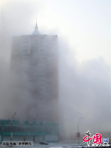 2013年12月17日，吉林省吉林市被大雾笼罩，城市建筑时隐时现，市民和车辆在雾霾中前行。中国网图片库 老万摄  