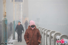 2013年12月17日，吉林省吉林市被大雾笼罩，城市建筑时隐时现，市民和车辆在雾霾中前行。中国网图片库 老万摄  