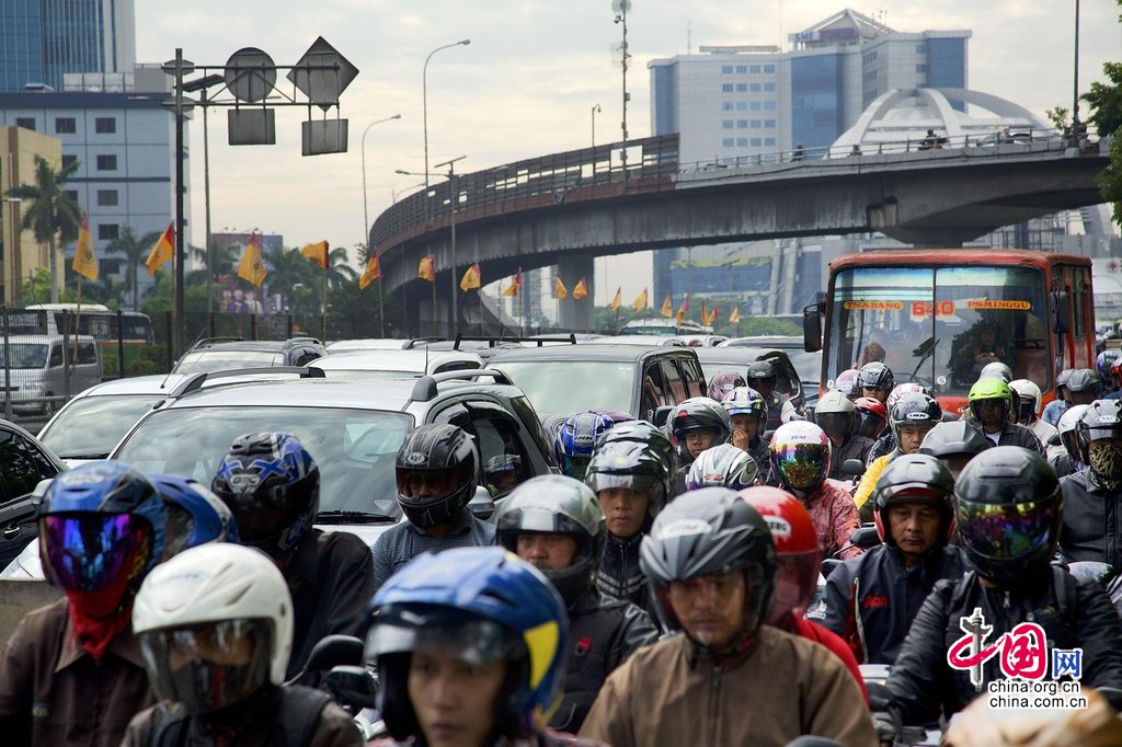 当地时间2013年12月19日，印尼雅加达，印尼民众行进在拥挤的道路上。