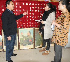 曾继红在家中向参观和欣赏他收藏毛泽东同志的20000枚像章、画像、雕塑和工艺品的群众介绍展品。 中国网图片库 王将 摄