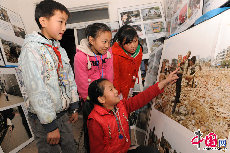 在连心社区的一个房间，挂满了由摄影师和社区孩子拍摄的照片，通过许多类似这样的兴趣活动，流动儿童增加了自信心，也丰富了课余生活。图为孩子们在活动中心欣赏拍摄的照片。中国网记者 佟静 摄