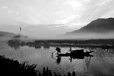 身披蓑衣的老唐站在船头捞鱼，在光影和雾气之中这样的画面也被摄影师捕捉到了。