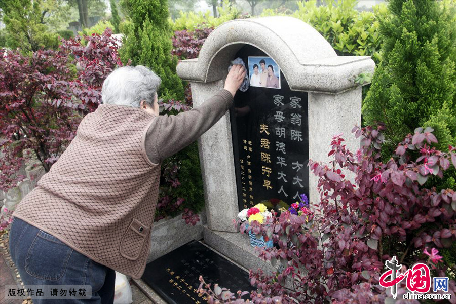 67歲的胡德華仔細的擦拭兒子的墓碑，嘴裏敘説對兒子的思念。中國網圖片庫 伏志勇/攝