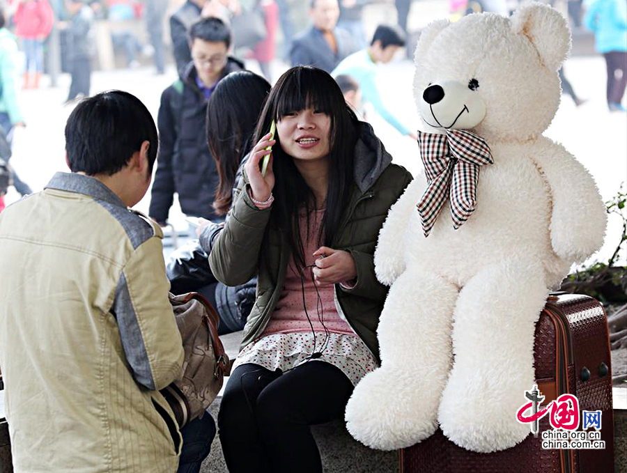 2014春运即将开始，重庆火车北站已人流涌动。图为在重庆火车北站候车厅外广场上一对情侣带着小白熊即将踏上回家之路。