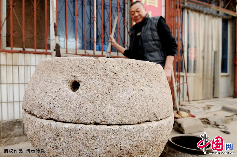  院子裏擺放著老崔收集來的“鼓磨”。鼓磨是大鼓形狀的磨盤，也是膠東鄉村裏常用的石制磨米工具。老崔説，他就是想讓現在的年輕人知道，過去的老人們是怎樣過著艱苦樸素的日子生活的。中國網圖片庫 王海濱/攝