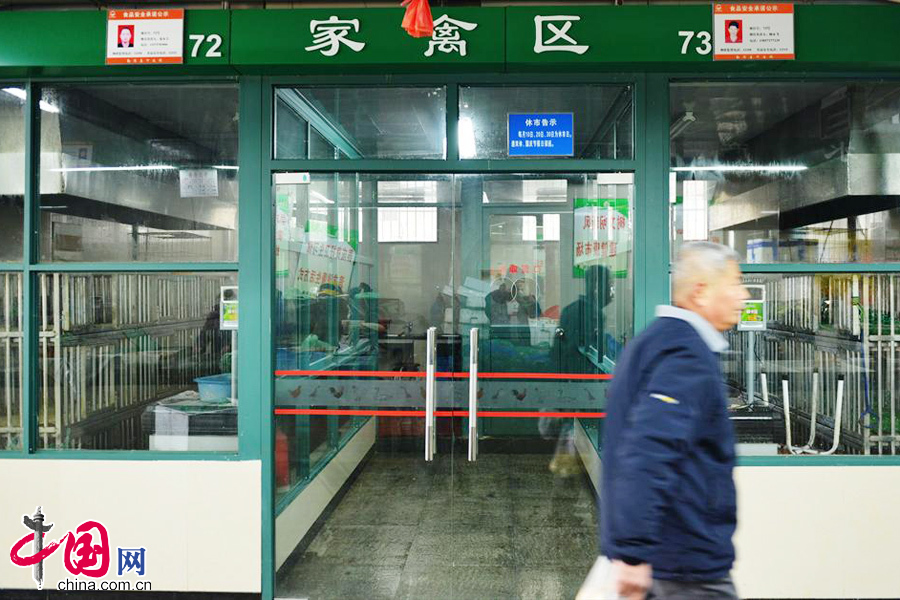 2014年01月24日，浙江省杭州市，市民从已关闭的杭州某农贸市场活禽交易摊位前走过。中国网图片库 龙巍摄影
