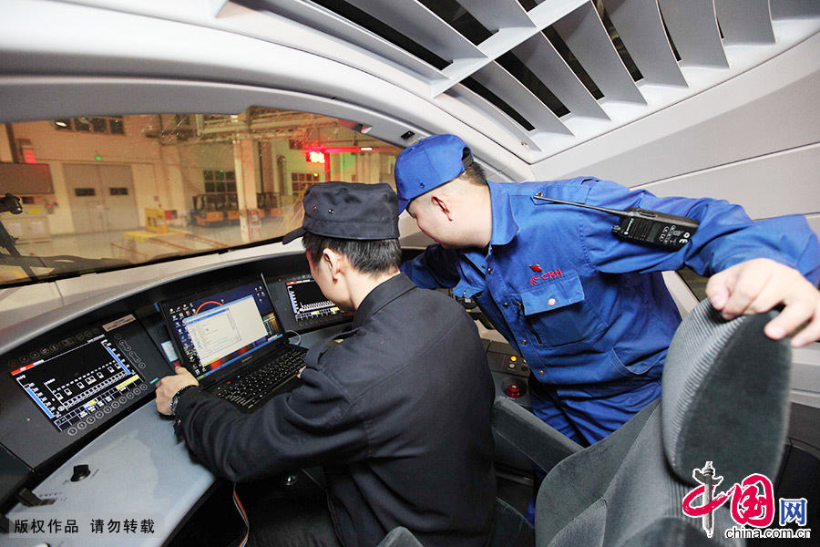  登上列车后，工作人员开始检查动车驾驶室。技术员（左）正在对动车运行数据进行下载，以便对运行途中的技术状态进行分析。中国网图片库 澎湃/摄