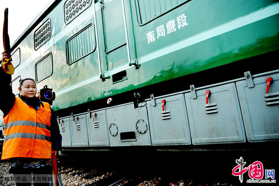 洪玫正在為火車頭打出通行旗語，她用這一原始的方式維持著火車的正常運作。中國網圖片庫 卓忠偉/攝