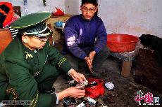 2014年2月14日，青島開發區薛家島邊防派出所幹警在幫助曹文峰整理被燒燬的殘幣。