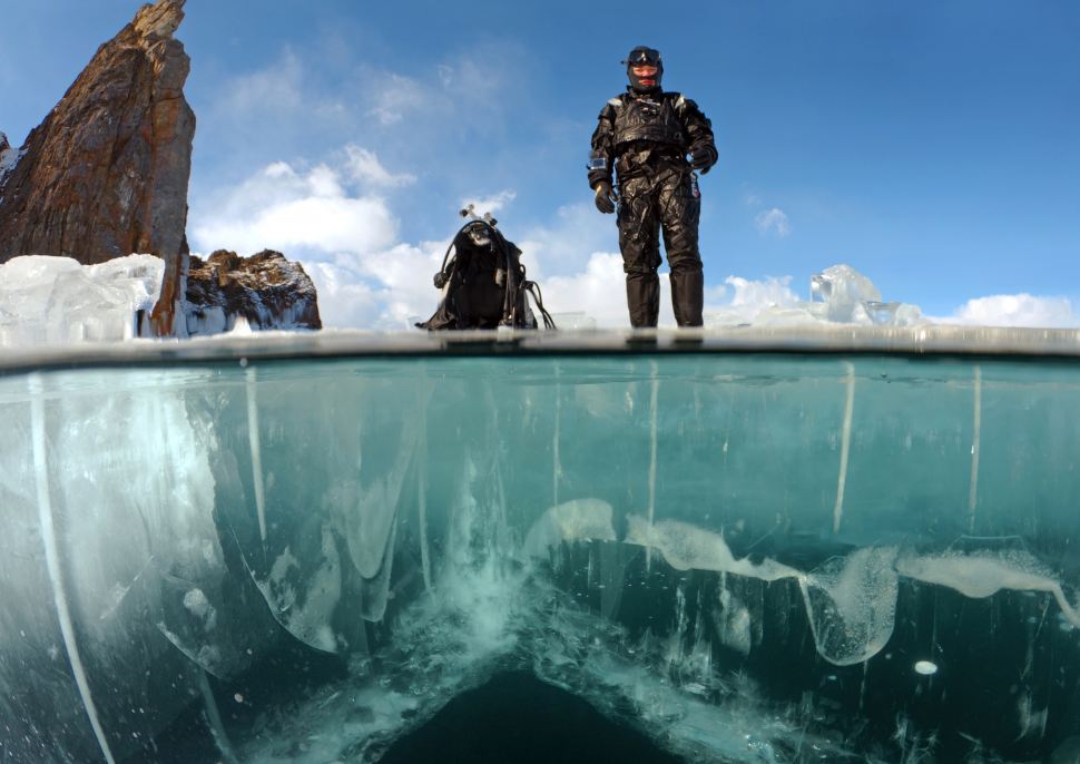 一名潜水员站在贝加尔湖的冰面上