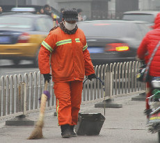 圖為環(huán)衛(wèi)工人戴著口罩清掃街道。